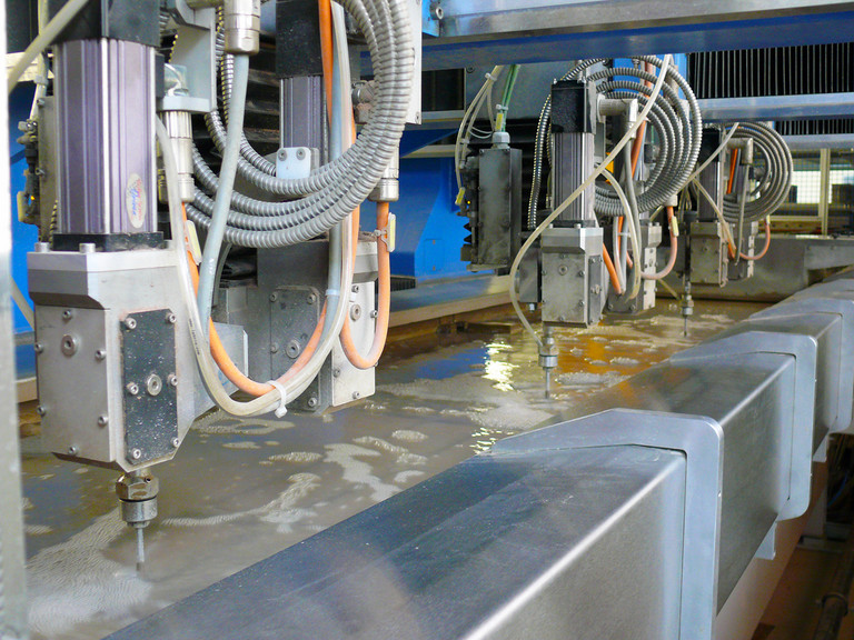 Wasserstrahlschneidmaschine mit 3 parallel laufenden, aber nicht fest verbundenen Wasserstrahlschneidköpfen gesteuert mit einer NUM Flexium CNC.