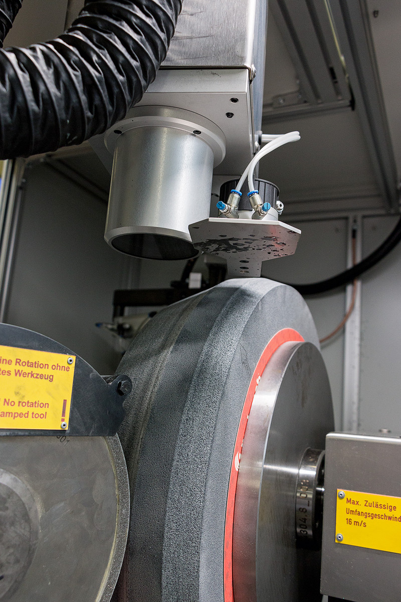 View of the AP900 - right, the large grinding wheel to be dressed - left, the silicon disk that precisely performs the dressing and profiling work on the grinding wheel. The profile that is being abraded by the silicon wheel can already be clearly recognized on the large grinding wheel. View of the AP900 - right, the large grinding wheel to be dressed - left, the silicon disk that precisely performs the dressing and profiling work on the grinding wheel. The profile that is being abraded by the silicon wheel can already be clearly recogni